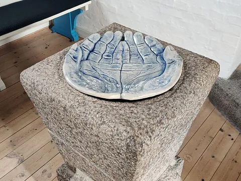 En keramisk skulptur af to åbne hænder, der er formet som en skål.