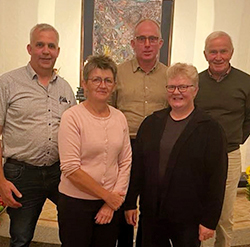Gruppenfoto von fünf Erwachsenen, die gemeinsam in einem Innenraum posieren.