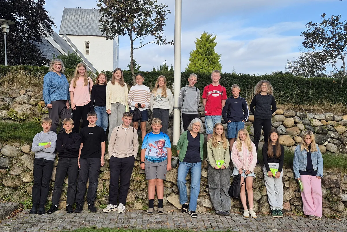 Kinder und Erwachsene posieren vor einem weißen Kirchengebäude.